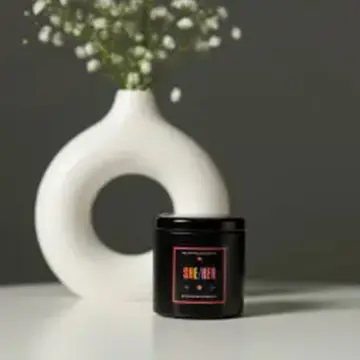 Black candle in a tin container.