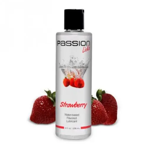 A bottle of strawberry flavored personal lubricant next to strawberries.