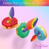 Rainbow spoons and donuts on pink background.