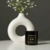 Black candle jar on white table.