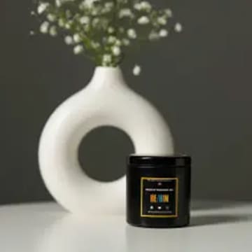 Black candle jar on white table.