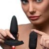 A woman is holding a black toy and looking at the camera.