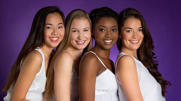 Portrait of four attractive mixed race women. Four women smiling against a purple background.